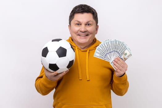 Man showing soccer ball and fun of hundred dollar bills, winning lot of money betting for sport.