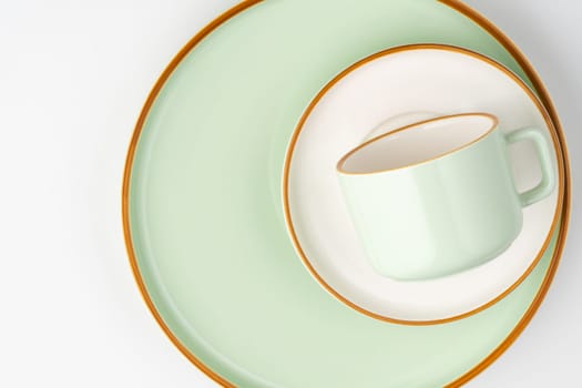 A set of white and pastel green ceramic tableware with orange outlines