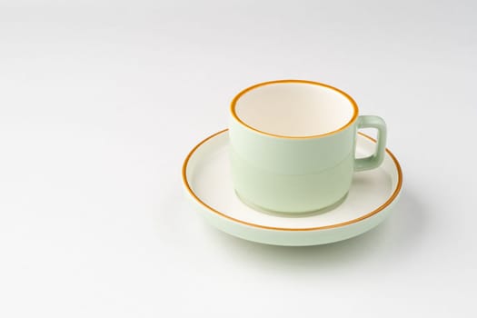 A white and pastel green ceramic teacup with orange outlines