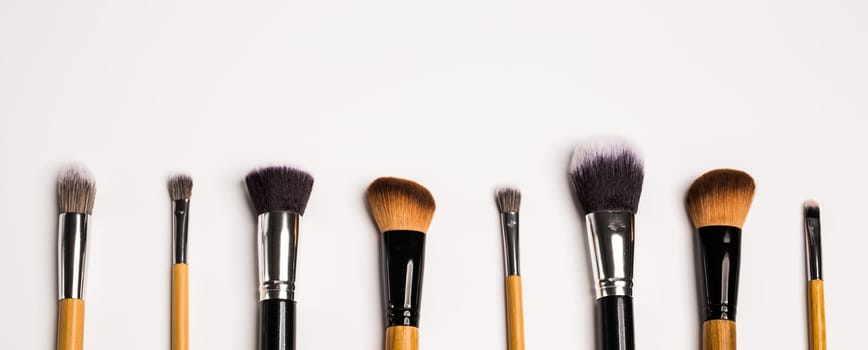 Assorted make up brushes isolated, top view banner. White background with copy space and empty space for text