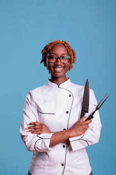 Smiling afro chef holding kitchen utensils