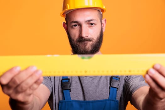 Confident male carpenter looking at construction leveler