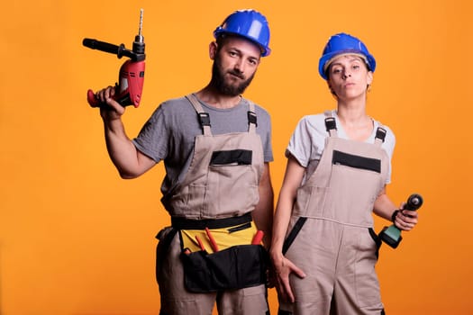 Man and woman renovators using drilling tools in studio