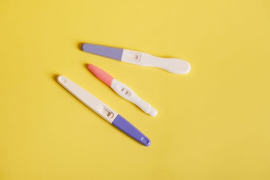 Pregnancy tests with positive result, isolated on yellow background. Planning pregnancy and maternity concept