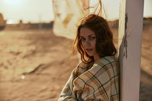 close portrait of a red-haired woman wrapped in a plaid in the rays of the setting sun