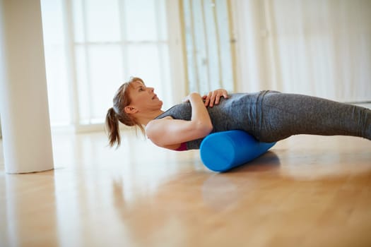 Strengthening her core muscles. a woman doing roller foam exercises during a yoga workout.