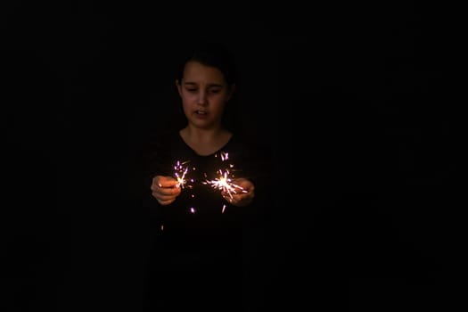 sad little girl with a sparkler in hand, Christmas. New year 2023