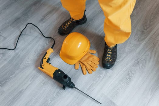 Handyman in yellow uniform with drill standing indoors. House renovation conception
