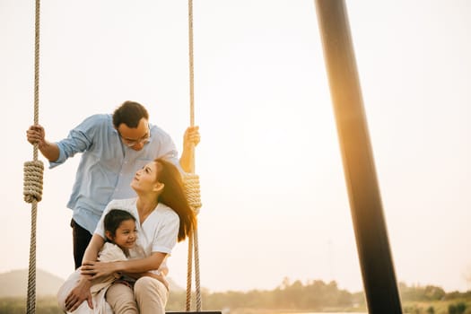Asian family swinging on a swing in a serene nature setting