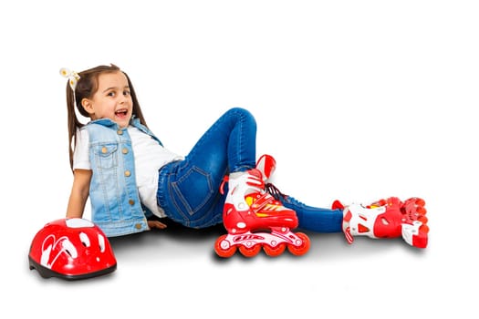 An adorable preschooler smiling though fallen while learning to roller skate. On a white background.