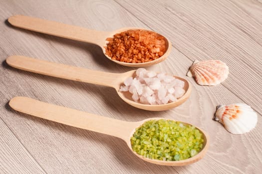 Wooden spoons with brown, white and green sea salt for bathroom procedures. Spa products and accessories