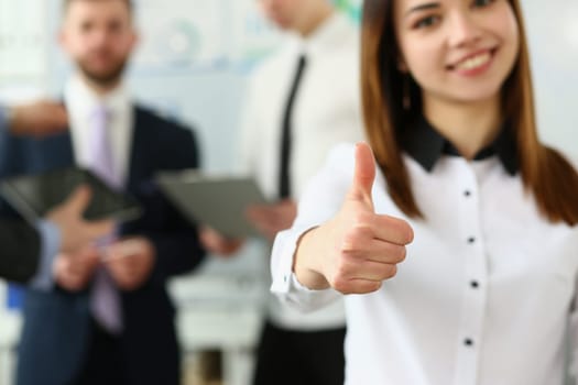 Businessman holds thumbs up in background are business partners