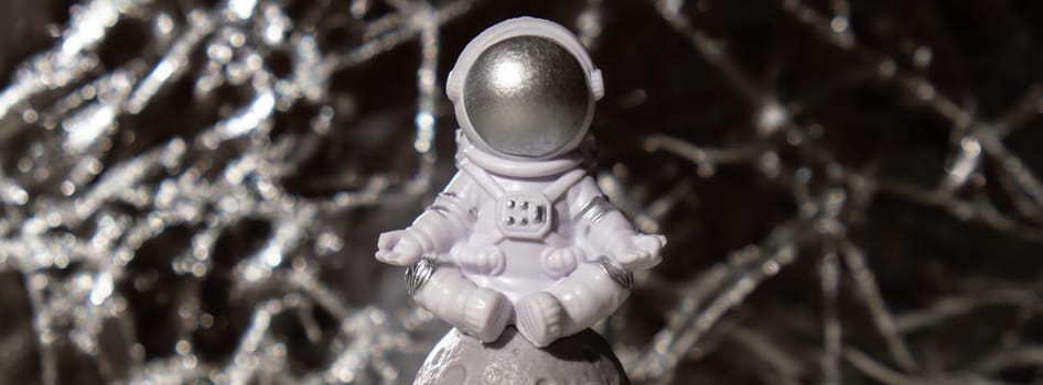 Plastic toy figure astronaut on silver background Copy space. Concept of out of earth travel, private spaceman commercial flights missions and Sustainability
