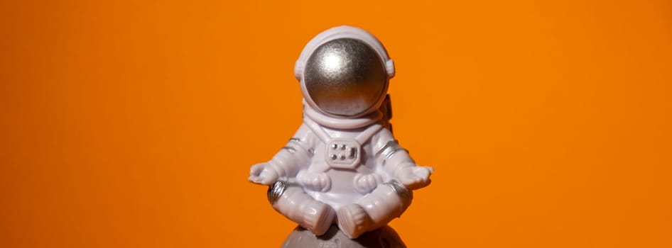 Plastic toy astronaut on colorful orange background Copy space. Concept of out of earth travel, private spaceman commercial flights missions and Sustainability