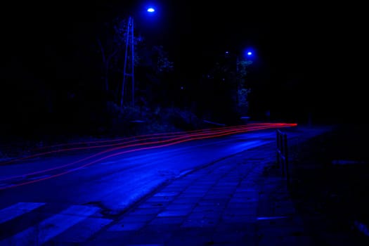 Lights of cars at night. Street line lights. Night highway city. Long exposure photograph night road. Colored bands of red light trails on the road. Background wallpaper defocused