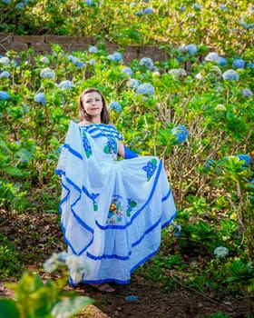 Nicaraguan woman in traditional folk costume in a field of flowers, Portrait of young Nicaraguan woman in traditional folk costume in a field of flowers