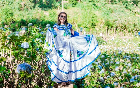 Smiling woman in national folk costume in a field surrounded by flowers. People in Nicaraguan national folk costume. Young Nicaraguan woman in traditional folk costume in a field of Milflores