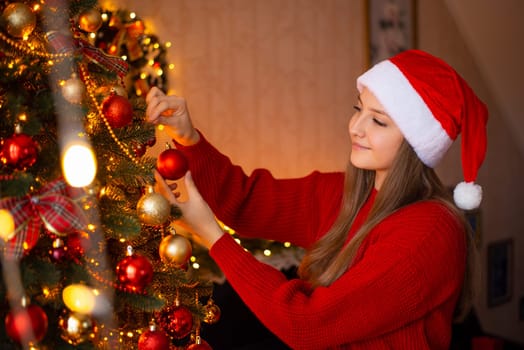 Young girl decorating Christmas tree at home