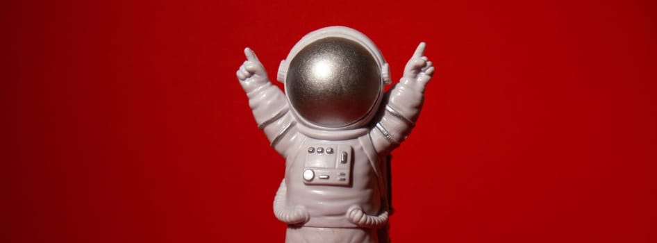Plastic toy astronaut on colorful red background Copy space. Concept of out of earth travel, private spaceman commercial flights missions and Sustainability