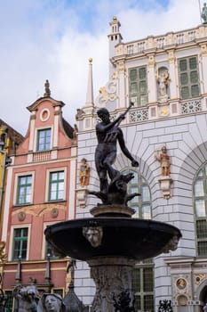 Artus court statue of Neptune fountain in City hall Ancient architecture of old town in Gdansk Poland. Beautiful and colorful old houses historical part of downtown