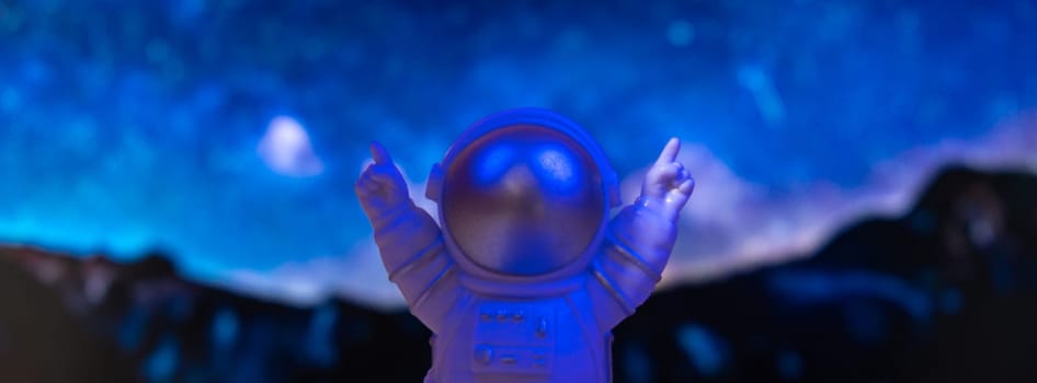 Plastic toy astronaut on universe planets background Copy space. Concept of out of earth travel, private spaceman commercial flights missions and Sustainability