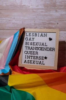 LGBTQIA description frame on Rainbow LGBTQIA flag made from silk material. LESBIAN, GAY, BISEXUAL, TRANSGENDER, QUEER, INTERSEX, ASEXUAL Symbol of LGBTQ pride month. Equal rights. Peace and freedom. Support LGBTQIA community