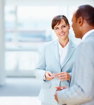 Female executive listening to colleague. Focus on female executive with male colleague in foreground.