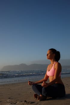 Let your soul experience serenity. a woman meditating on the beach.