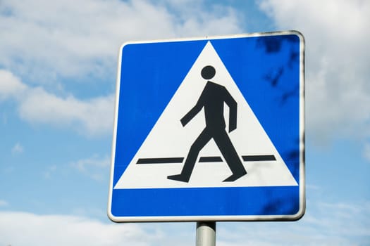 Vertical signage of crosswalk over cloudy sky, road sign pedestrian crossing. Attention road sign