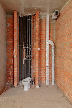 Repair and restoration of apartments. Red brick walls, concrete floors. Drain pipes and toilet.