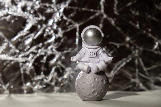 Plastic toy figure astronaut on silver background Copy space. Concept of out of earth travel, private spaceman commercial flights missions and Sustainability