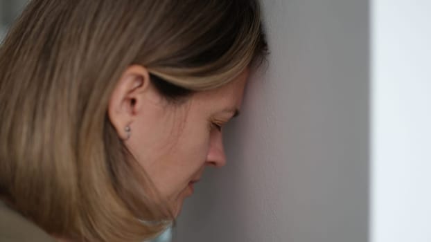 Woman with depression and stress banging head against wall at home