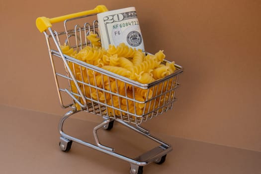 Shopping trolley cart Filled With Pasta with 20 US dollar paper money banknote on Beige background. Copy space for your text. Food and groceries shopping price increase, Rising food cost food crisis inflation concept. Online shopping, buy mall