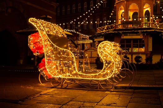 Santa Claus Sleigh Holiday Decorated and illuminated street at night in Gdansk Poland. Beautiful Christmas fair in the old town at night. Advent winter time in Europe background. Markets in December Ornamented for celebration