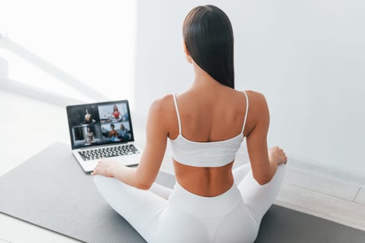 With laptop. Young caucasian woman with slim body shape is indoors at daytime