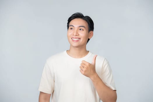 Nice smile friendly Asian man in white t-shirt giving thumbs up