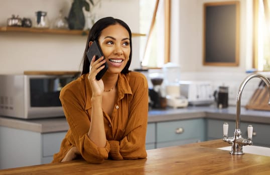 Happy woman, phone call and kitchen in a home in a conversation. House, female and smile of a person with joy resting on a counter feeling relax and happiness on a mobile talking and communication.