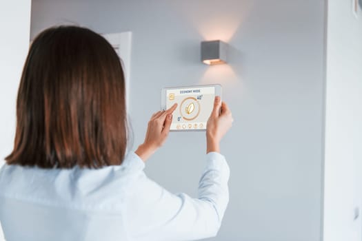 Rear view of woman that is indoors controlling smart home technology