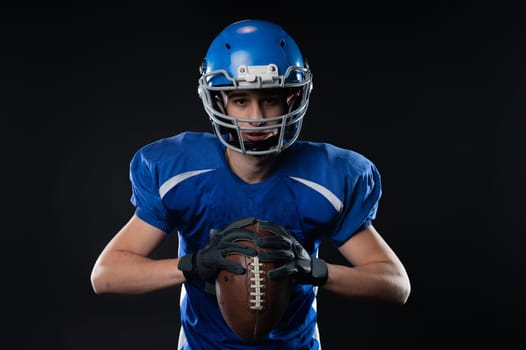 Portrait of a man in a blue uniform for american football on a black background.