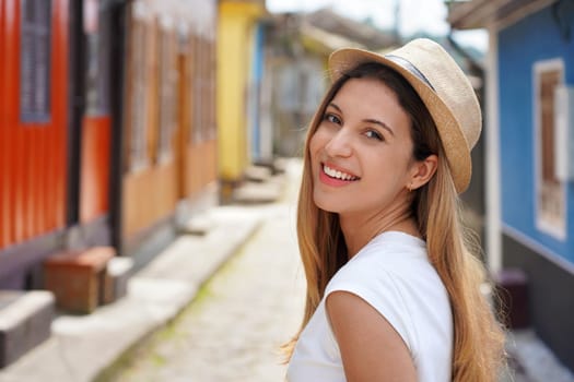 Close-up of happy young tourist woman turns around and smile at camera outdoor