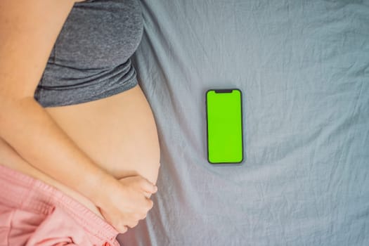 Pregnant girl with a smartphone. The concept of a negative impact on the unborn child in the womb. Violation of the nervous system of the child, reproductive