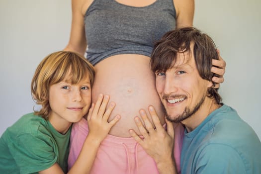 Father and elder son listen to mom's pregnant belly