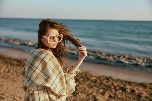 portrait of a woman in a plaid holding her hair in the wind against the backdrop of a seascape