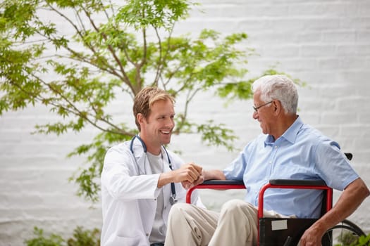 Giving his patient a positive outlook. a male doctor talking to his senior patient whos in a wheelchair outside.