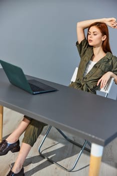 a puzzled woman sits at a laptop with her hand raised to her head