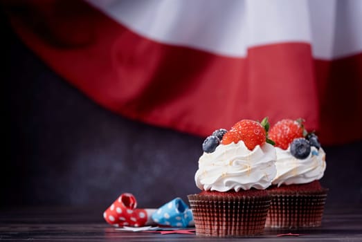 Sweet cupcakes with blueberries and strawberry over USA flag background