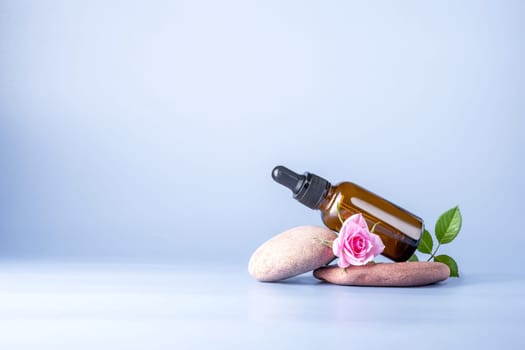 Glass bottle with pipette for a cosmetic product with a rose on stones
