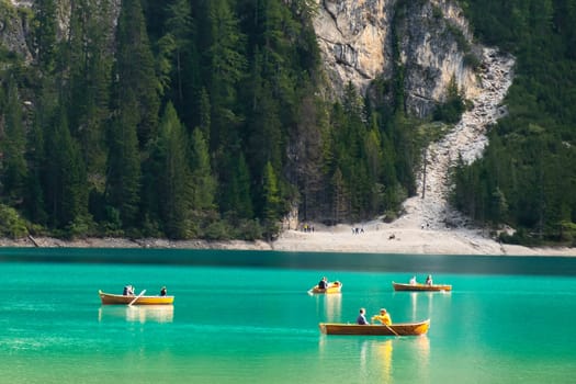 Tourists ride wooden boats on Braies lake