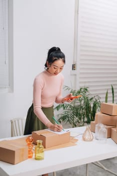 Women packing package with her products that she selling online