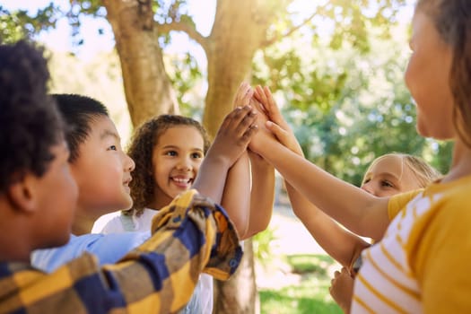 Happy, playing and children with a high five for a game, support and team building at a park. Smile, together and friends with hands for motivation, connection and celebration at a summer camp.